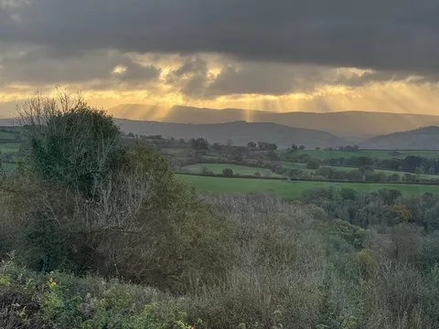 Golau dros y bryniau gerllaw